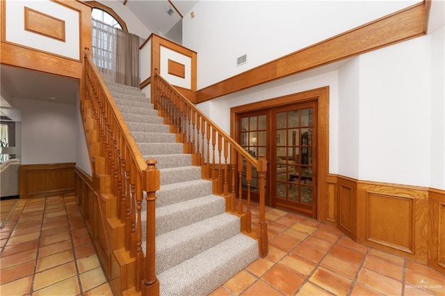 stairway featuring tile patterned flooring and high vaulted ceiling