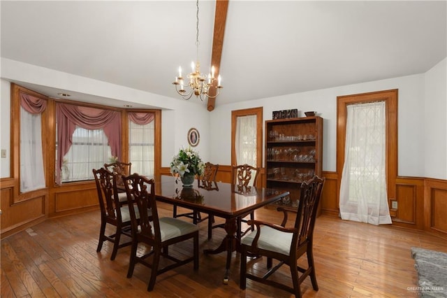 dining room with beamed ceiling, a notable chandelier, and hardwood / wood-style flooring