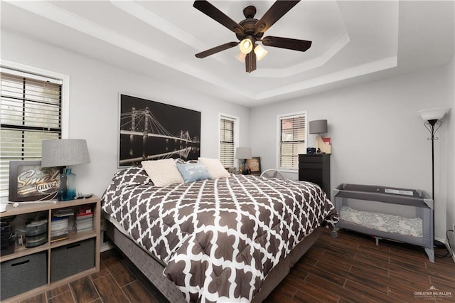 bedroom featuring dark hardwood / wood-style flooring, a raised ceiling, and ceiling fan