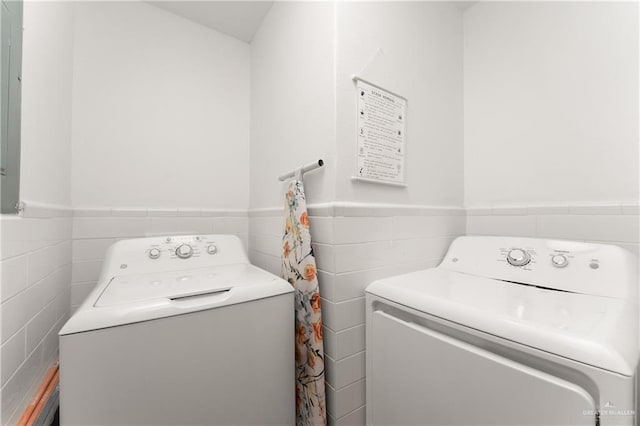 clothes washing area featuring independent washer and dryer and tile walls