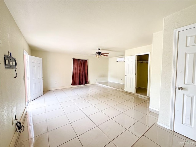 tiled spare room with a wall mounted AC and ceiling fan