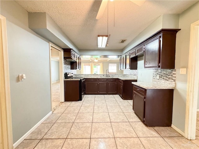 kitchen featuring sink, backsplash, dark brown cabinetry, and stainless steel range with electric stovetop