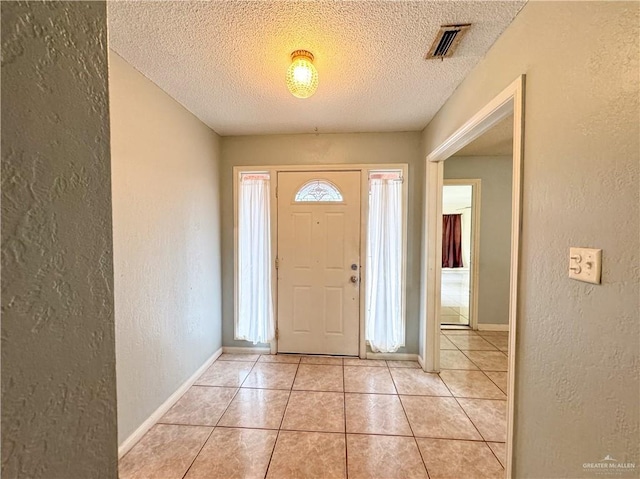 foyer entrance with a healthy amount of sunlight, light tile patterned floors, and a textured ceiling