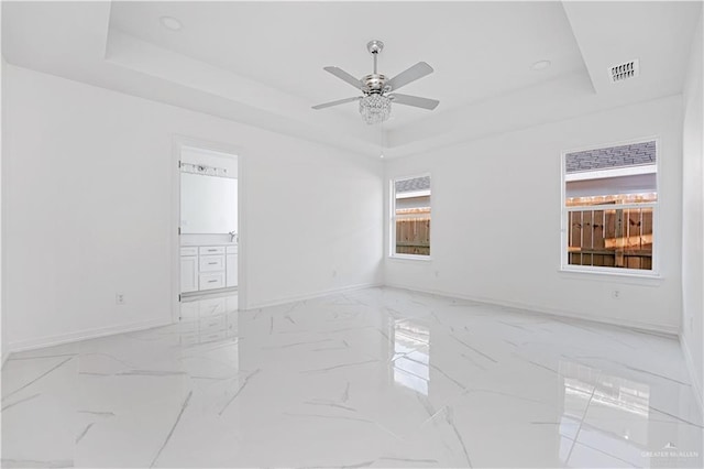 spare room with a raised ceiling and ceiling fan