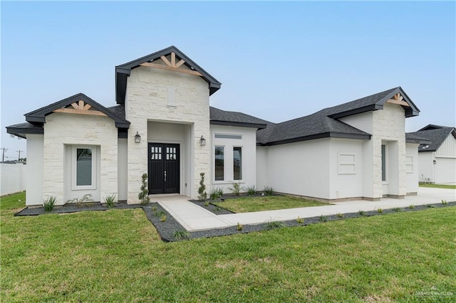 view of front of house featuring stone siding, a shingled roof, and a front lawn