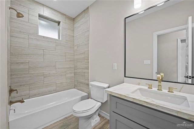 full bathroom featuring vanity, hardwood / wood-style floors, tiled shower / bath combo, and toilet