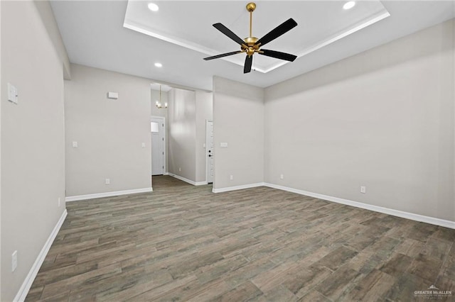 unfurnished room featuring dark hardwood / wood-style floors, ceiling fan, and a tray ceiling