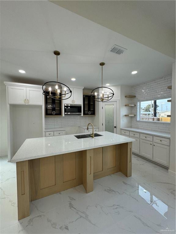 kitchen featuring a large island with sink, white cabinetry, pendant lighting, and sink