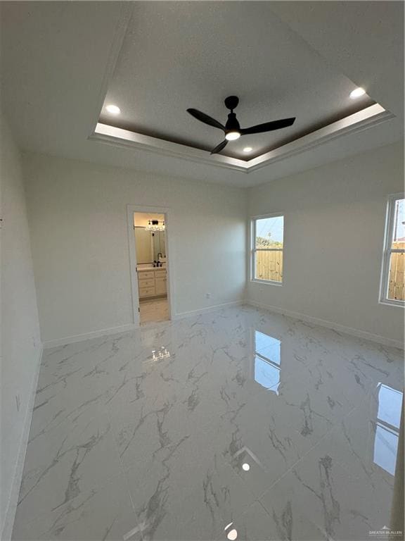 empty room featuring a raised ceiling and ceiling fan