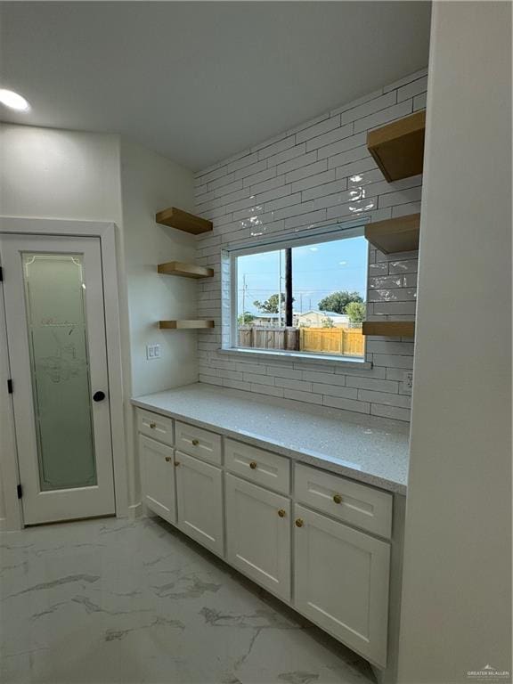 kitchen with decorative backsplash, white cabinets, and light stone counters