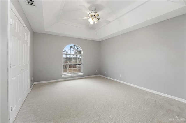 carpeted spare room with ceiling fan and a tray ceiling