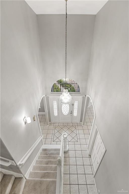 tiled foyer featuring a towering ceiling and a chandelier