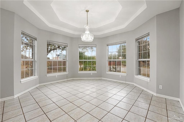 unfurnished dining area featuring light tile patterned floors, a notable chandelier, and a tray ceiling