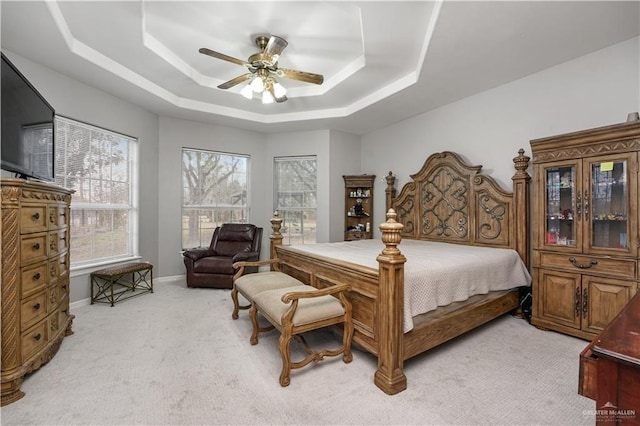 carpeted bedroom featuring a raised ceiling and ceiling fan