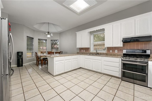 kitchen with light tile patterned flooring, appliances with stainless steel finishes, sink, white cabinets, and kitchen peninsula