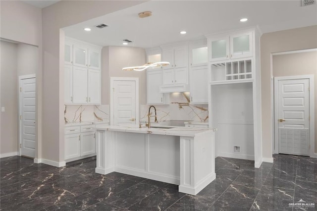 9510 N 71st Ln, Mcallen, TX 78573 - kitchen with dark marble finish floors, a kitchen island with sink, white cabinets, glass insert cabinets, and recessed lighting
