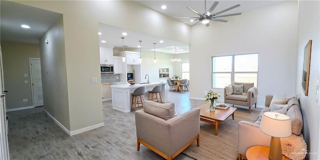 living room featuring ceiling fan, sink, and light hardwood / wood-style flooring