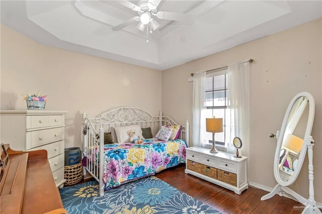 bedroom with ceiling fan, dark hardwood / wood-style flooring, and a raised ceiling