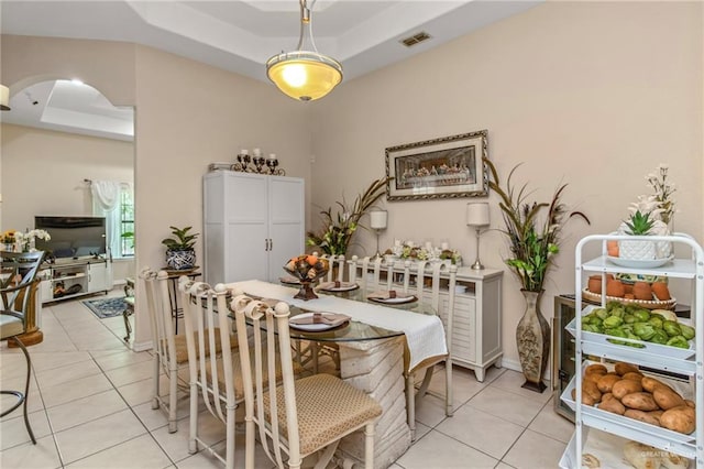 tiled dining area with a tray ceiling