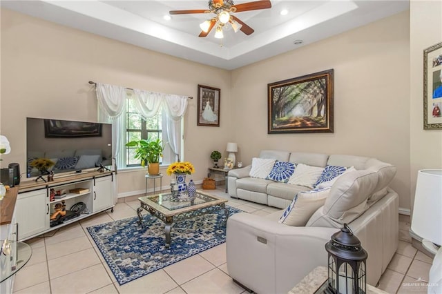 living room with ceiling fan, light tile patterned floors, and a tray ceiling