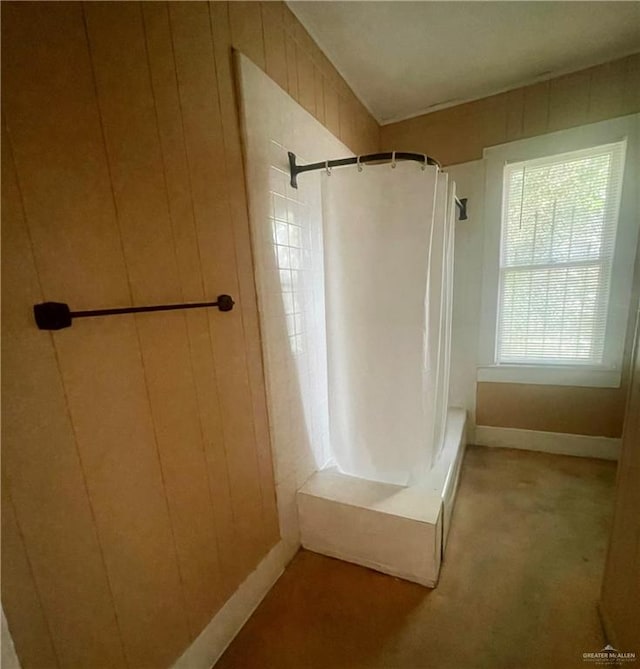 bathroom with walk in shower and wood walls