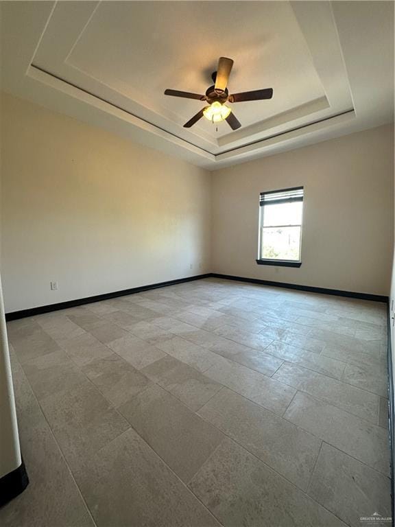 empty room featuring ceiling fan and a raised ceiling