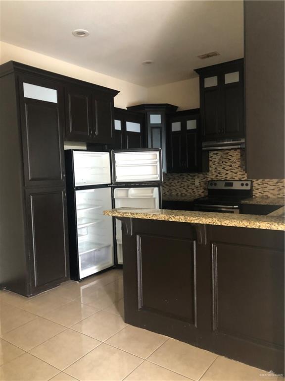 kitchen with decorative backsplash, light stone countertops, light tile patterned floors, and stainless steel appliances