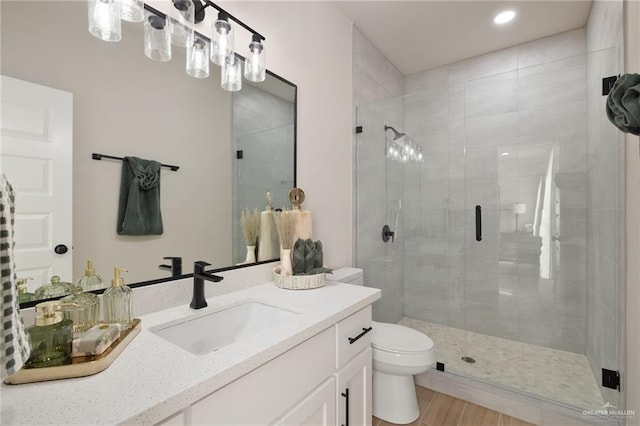 bathroom featuring vanity, toilet, and a shower with door