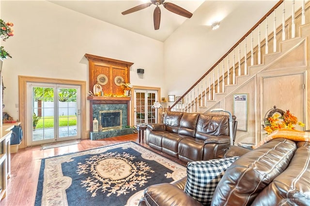 living room featuring french doors, ceiling fan, hardwood / wood-style flooring, high vaulted ceiling, and a fireplace