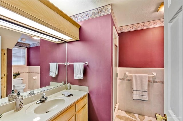 bathroom with vanity, toilet, and tile walls