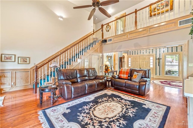 living room featuring ceiling fan, a towering ceiling, and hardwood / wood-style flooring