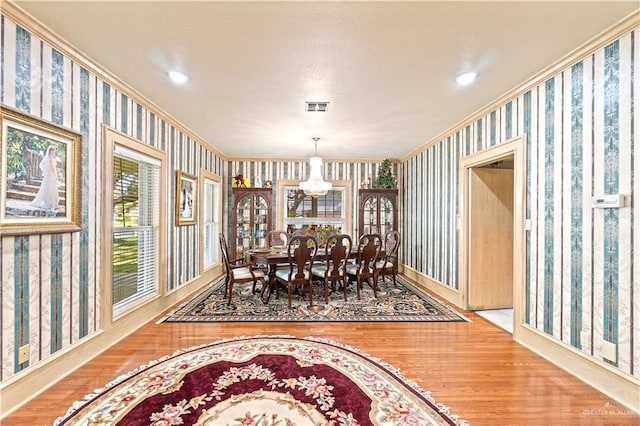 dining room with hardwood / wood-style floors, ornamental molding, and an inviting chandelier