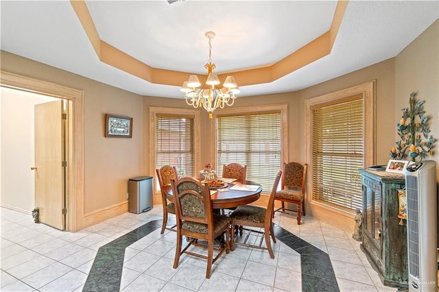 dining space with a raised ceiling, a wealth of natural light, and light tile patterned flooring