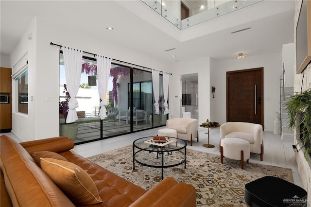 living area featuring baseboards, a high ceiling, recessed lighting, and visible vents