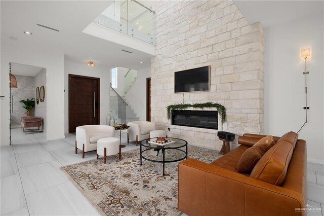 living room featuring a large fireplace, a high ceiling, and stairs
