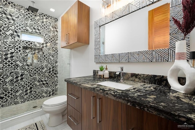 bathroom featuring vanity, tile patterned flooring, toilet, and tiled shower