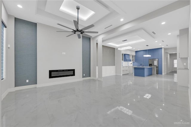 3005 N Alyna Ave, Edinburg, TX 78541 - unfurnished living room with a raised ceiling, light marble finish floors, ceiling fan, a glass covered fireplace, and recessed lighting