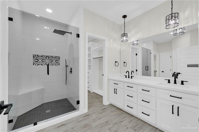 full bath featuring a sink, double vanity, wood finished floors, and a shower stall