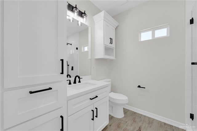 full bathroom with baseboards, toilet, wood finished floors, vanity, and a shower