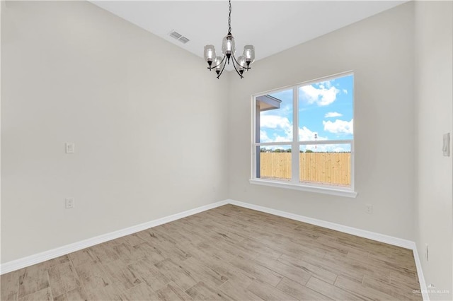 unfurnished room featuring visible vents, light wood-style floors, baseboards, and a chandelier