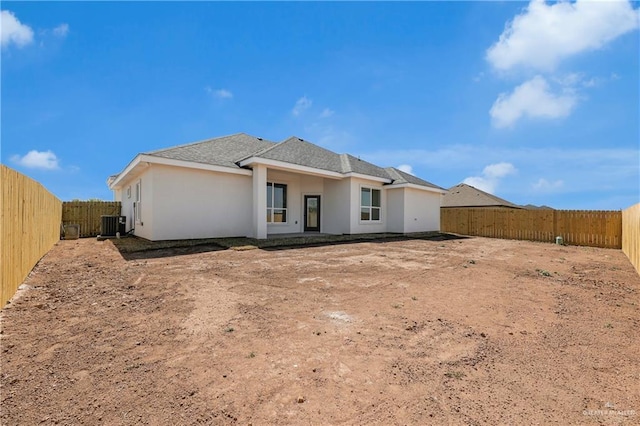 back of property with central AC unit, a fenced backyard, and stucco siding