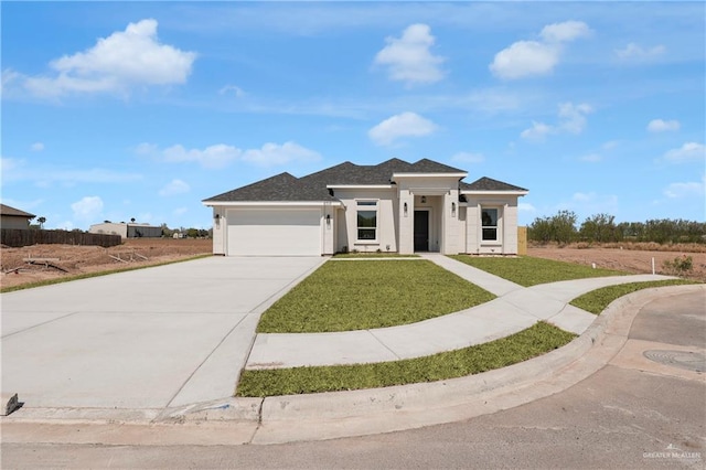 prairie-style home with driveway, a front yard, and an attached garage