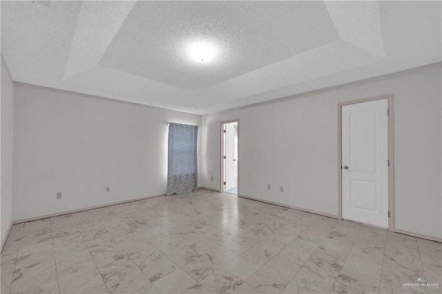 empty room with a raised ceiling and a textured ceiling