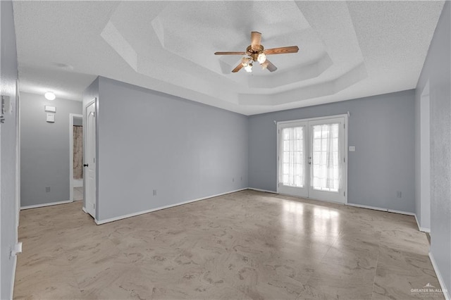 spare room with a tray ceiling, a textured ceiling, french doors, and ceiling fan