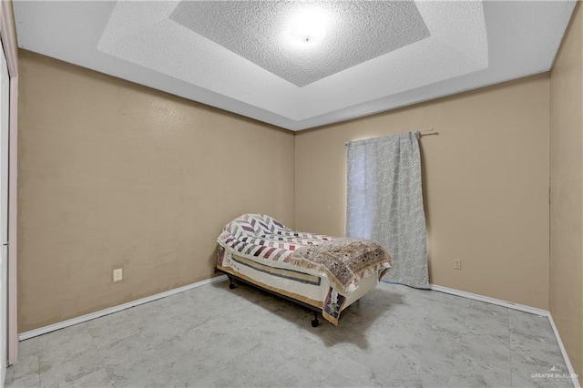 bedroom featuring a tray ceiling and a textured ceiling