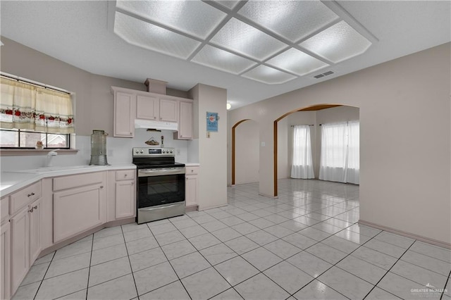 kitchen with sink, light tile patterned floors, white cabinetry, a wealth of natural light, and stainless steel range with electric cooktop