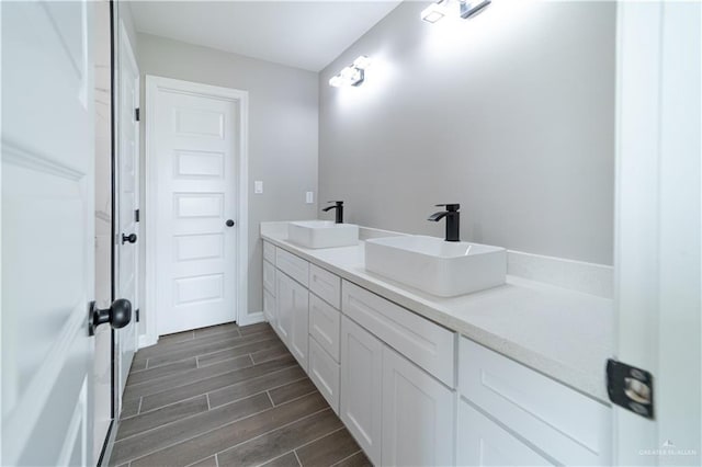 full bath featuring double vanity, wood tiled floors, and baseboards