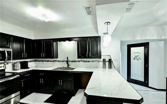 kitchen featuring sink, light stone counters, backsplash, decorative light fixtures, and appliances with stainless steel finishes