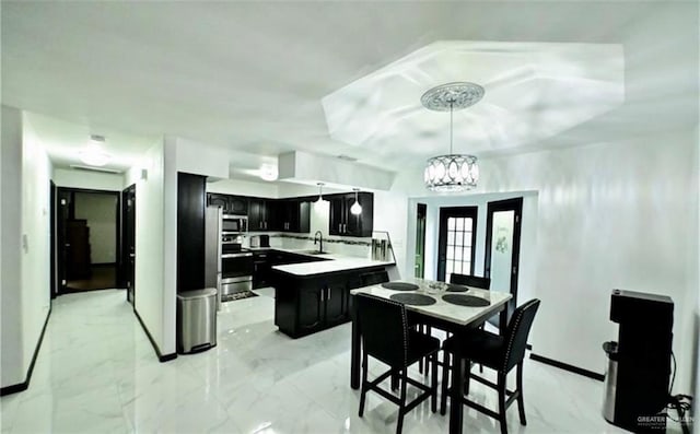 kitchen featuring appliances with stainless steel finishes, sink, a chandelier, a center island, and hanging light fixtures