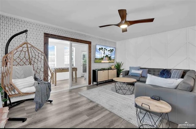 living room featuring hardwood / wood-style floors, ceiling fan, and crown molding